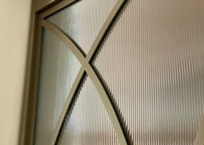 Skygate Flow – detailfoto van stalen deur met gebogen lijnen, metallic bonded bronze en ribglas, hoge precisieafwerking