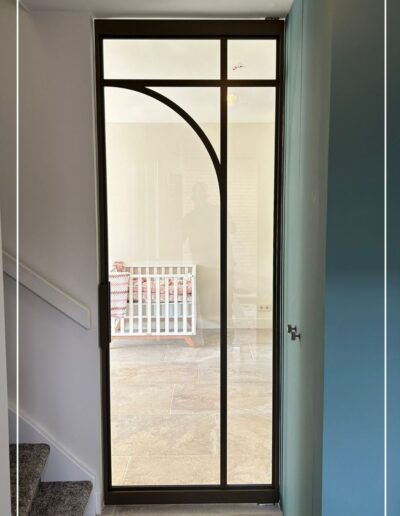 Ronde stalen deur met geronde vormen en glas uit de Flow Collectie