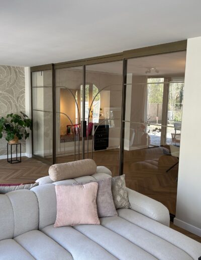 Skygate glazen schuifwand met stalen profielen, maatwerkdesign in warme interieurstijl met natuurlijke tinten en glas.