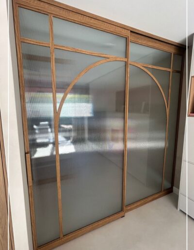 Stalen schuifpui van Skygate: houtlook gecombineerd met geribbeld glas, vast paneel en schuifdeur in natuurlijke stijl.