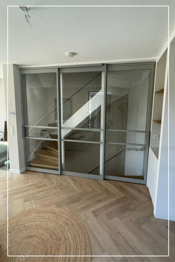Maatwerk stalen schuifdeuren in lichtgrijze afwerking bij woonkamer en trap – Skygate binnendeuren met glas