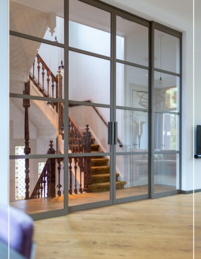 Maatwerk stalen schuifwand in metallic bronze tussen hal en woonkamer