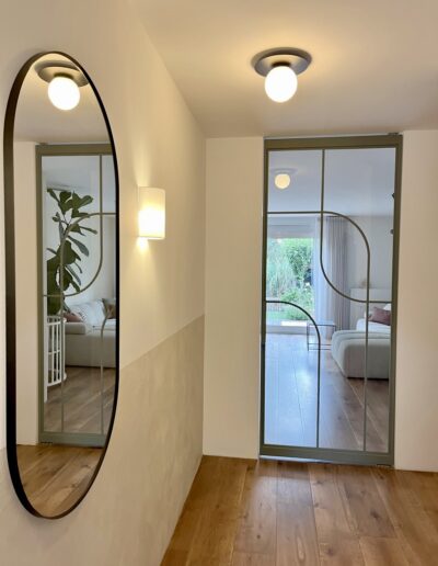 Hal met Skygate stalen taatsdeur in RAL 7033 cementgrijs, moderne entree met glas en maatwerk design.