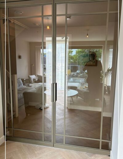 Dubbele stalen schuifdeur in metallic bonded bronze met brons glas in woonkamerwand