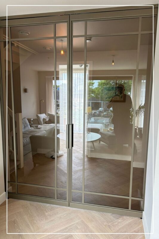 Dubbele stalen schuifdeur in metallic bonded bronze met brons glas in woonkamerwand