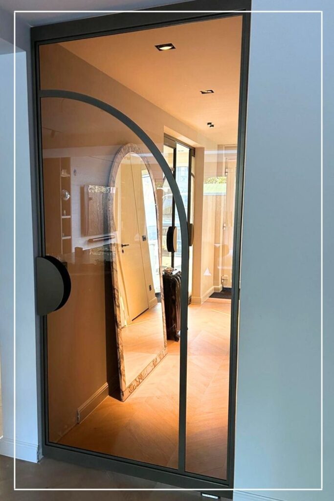 Skygate Flow stalen taatsdeur met organische profielen en helder glas tussen hal en woonkamer.