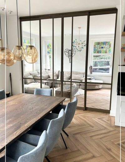 Skygate stalen schuifpui in metallic bonded bronze, maatwerkdesign tussen eetkamer en woonkamer met helder glas.