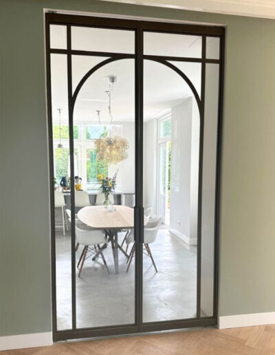 Skygate dubbele taatsdeuren in Metallic Bonded Brons met helder glas als stijlvolle afscheiding tussen woonkamer en woonkeuken.