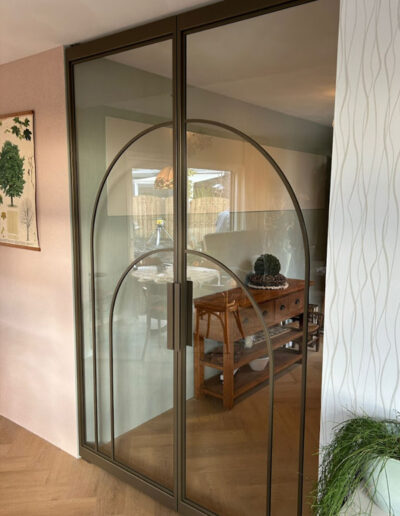 Skygate dubbele taatsdeuren in eigen Flow-ontwerp, maatwerk in Metallic Bonded Brons met helder glas tussen hal en eetkamer.