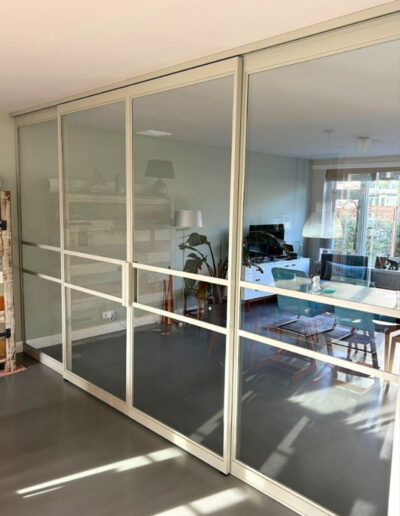Skygate Classic design schuifpui in RAL wit, maatwerk uitvoering tussen woonkamer en eetkamer met helder glas.