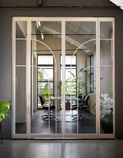 Skygate dubbele taatsdeur met zijpanelen in Flow-design, Bonded Brons uitgevoerd met helder glas, getoond in de showroom.