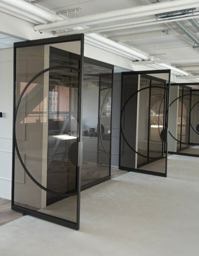 Skygate XL taatsdeur in Metallic Brown, Flow-design met brons getint glas tussen twee vergaderruimtes.