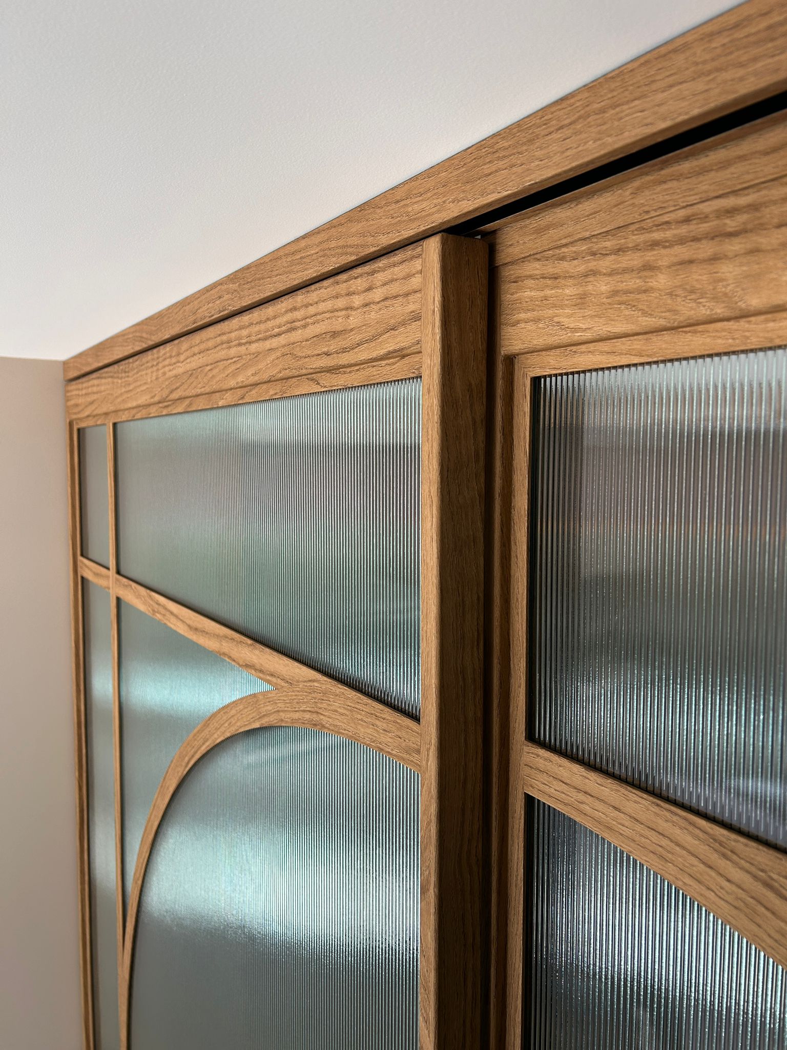 Skygate detail van houtlook schuifpui op maat met ribglas en ronde vorm in de keuken.