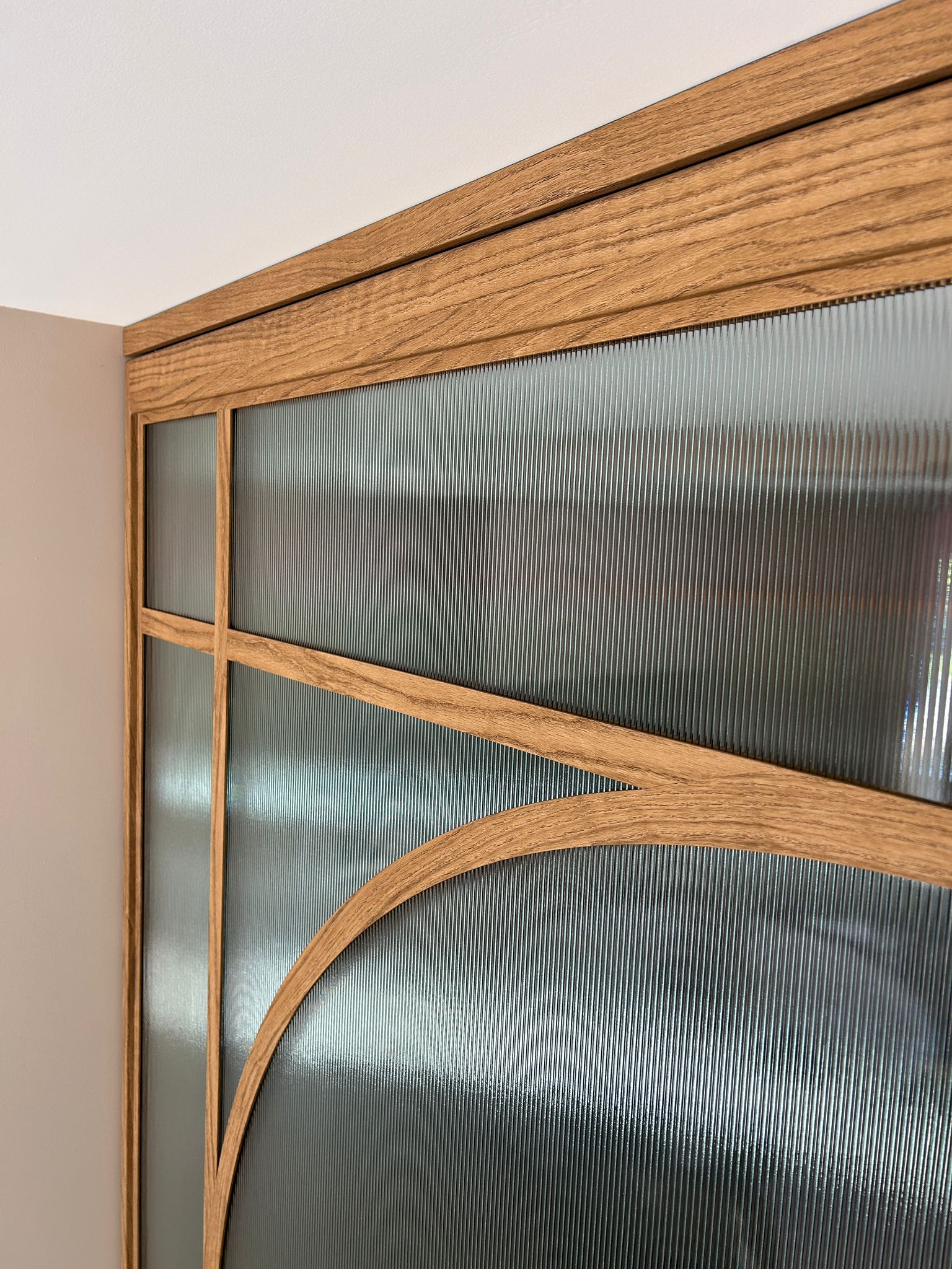 Skygate detail van houtlook schuifpui met ribglas en ronde vorm in luxe keuken.
