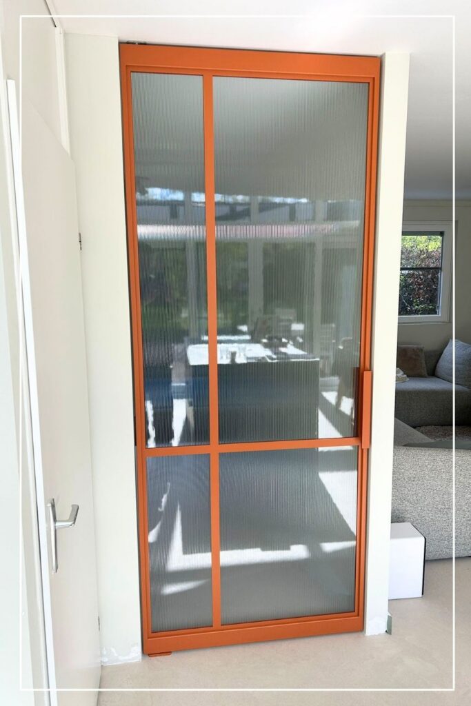 Oranje stalen taatsdeur met ribbelglas van Skygate