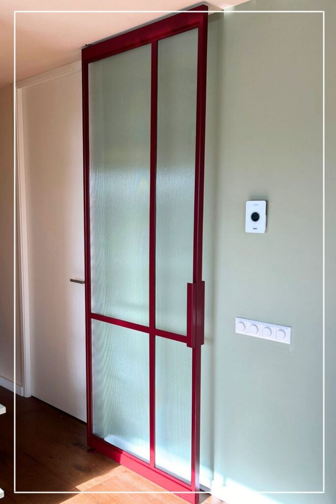 Rode stalen taatsdeur model No. 7 met ribbelglas van Skygate in een modern interieur