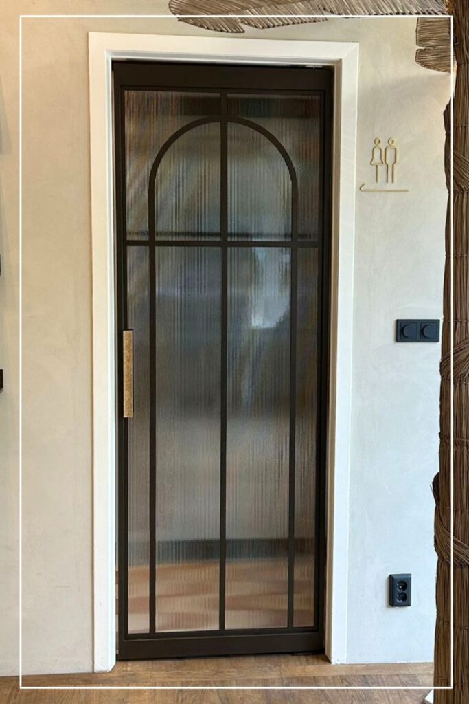 Stalen taatsdeur met eigen design en ribbelglas van Skygate in een interieur met boogvormige lijnverdeling