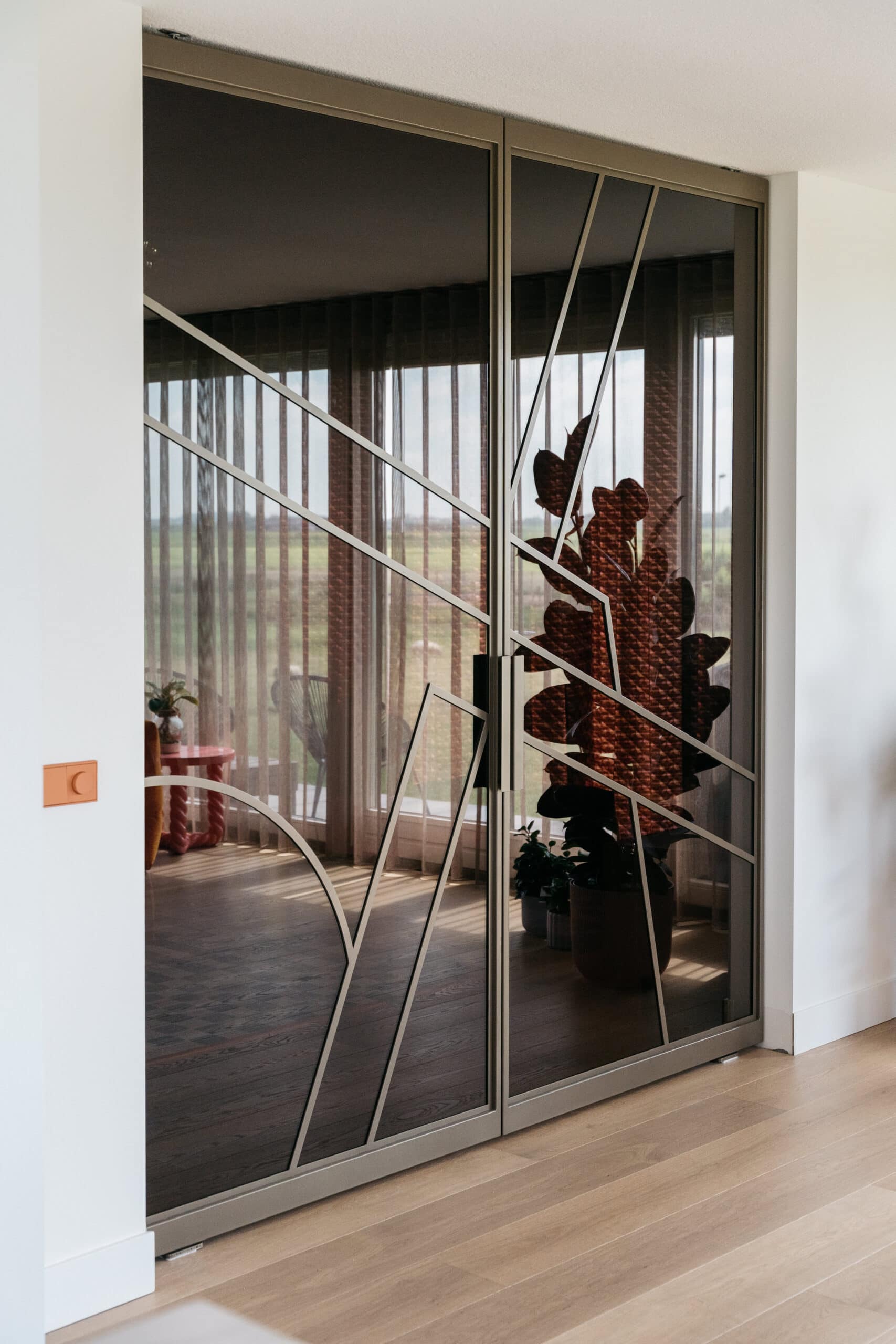 Skygate taatsdeur op maat in metallic brown met ribglas en Flow design bij houten vloer