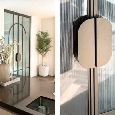Dubbele stalen taatsdeuren met verticaal ribbelglas en een stijlvol rond deurgreepdesign.